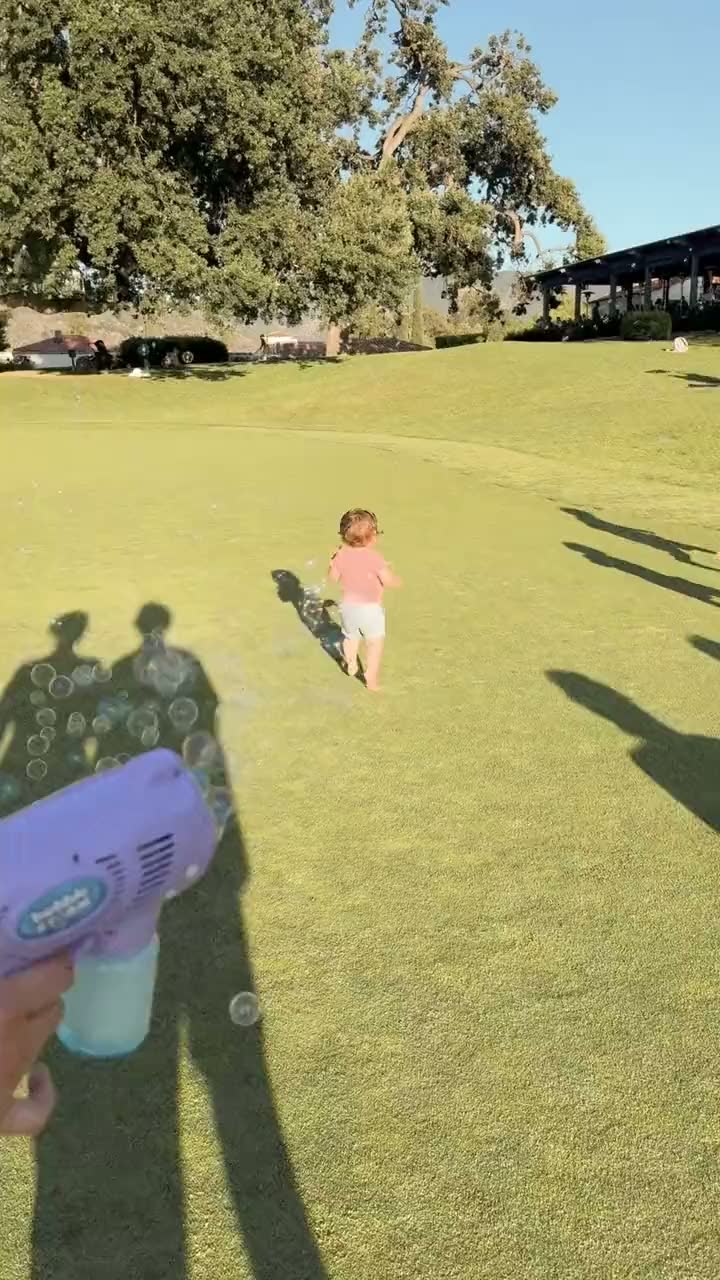 A short clip of a toddler running across the wide lawn below Jimmy's Pub at Ojai Valley Inn while bubbles drift across the grass in late afternoon light