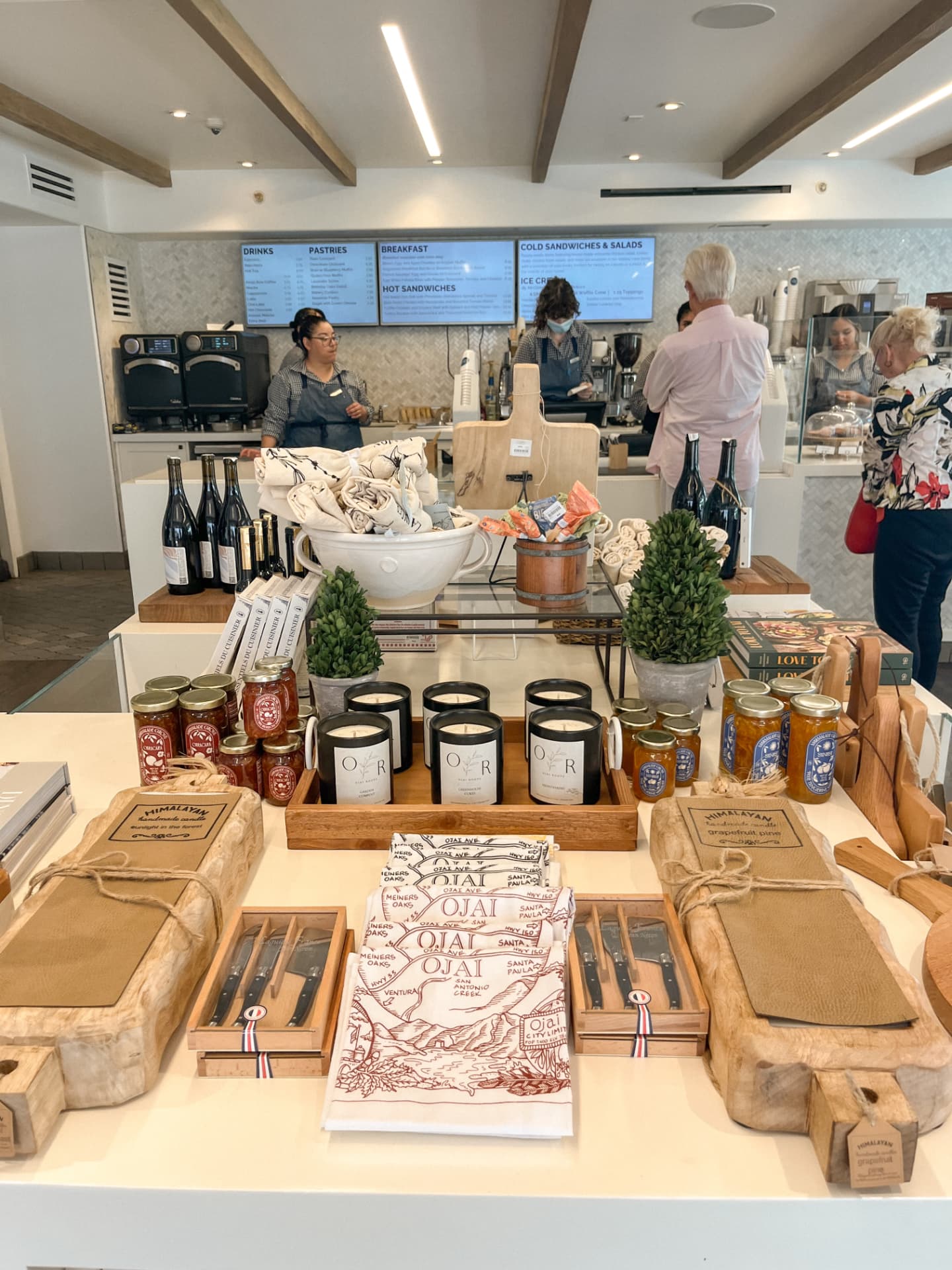The small market on the property, with a coffee and sandwich counter and menu boards at the back and a front table of jams, candles, tea towels and boards