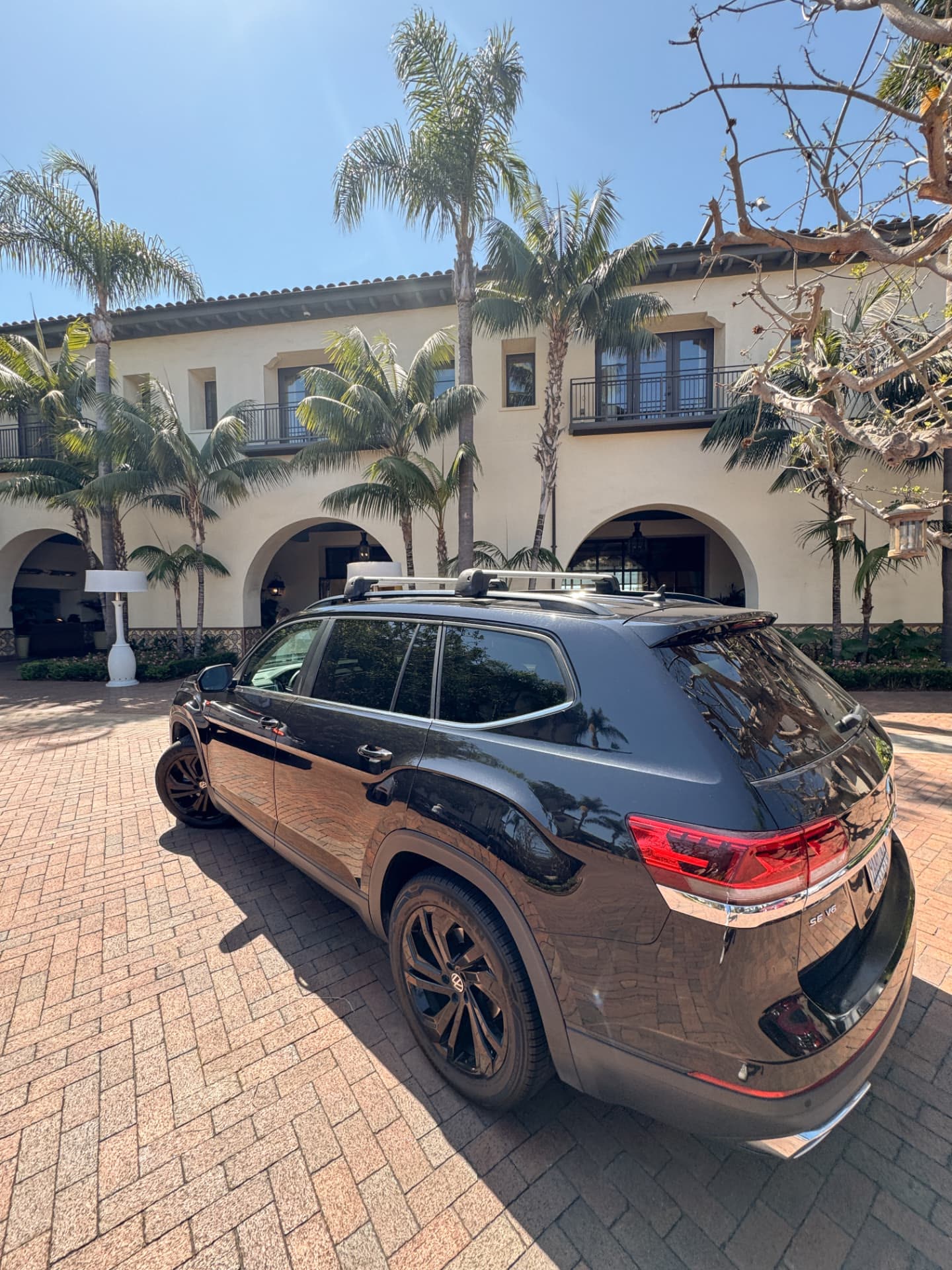 Our car at the arrival courtyard at Terranea Resort, with palms and the stone arches of the entrance behind it