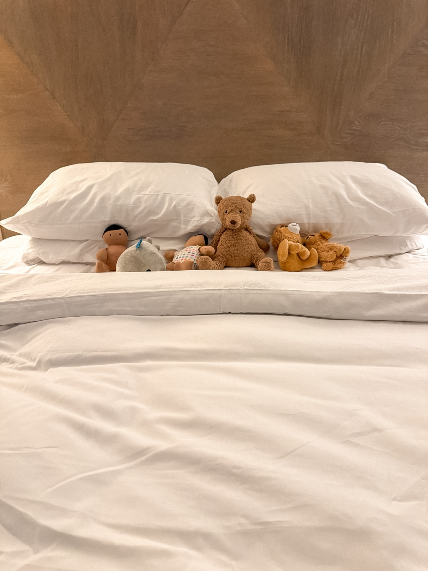 Stuffed animals on a lived-in hotel bed