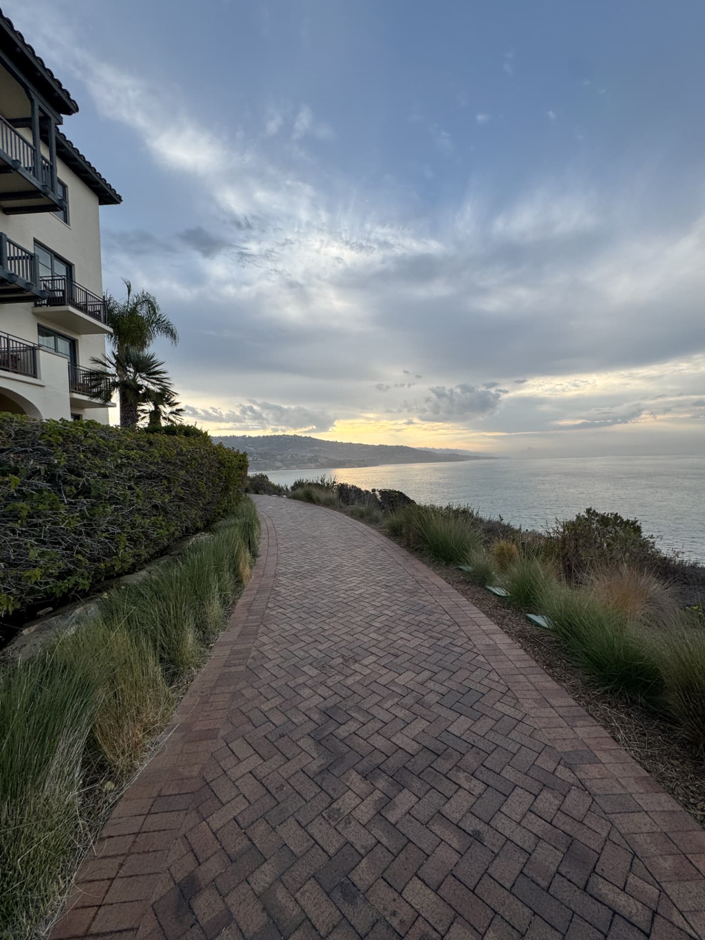 A wide brick coastal path at Terranea at dusk, with casitas on one side and the coastline ahead