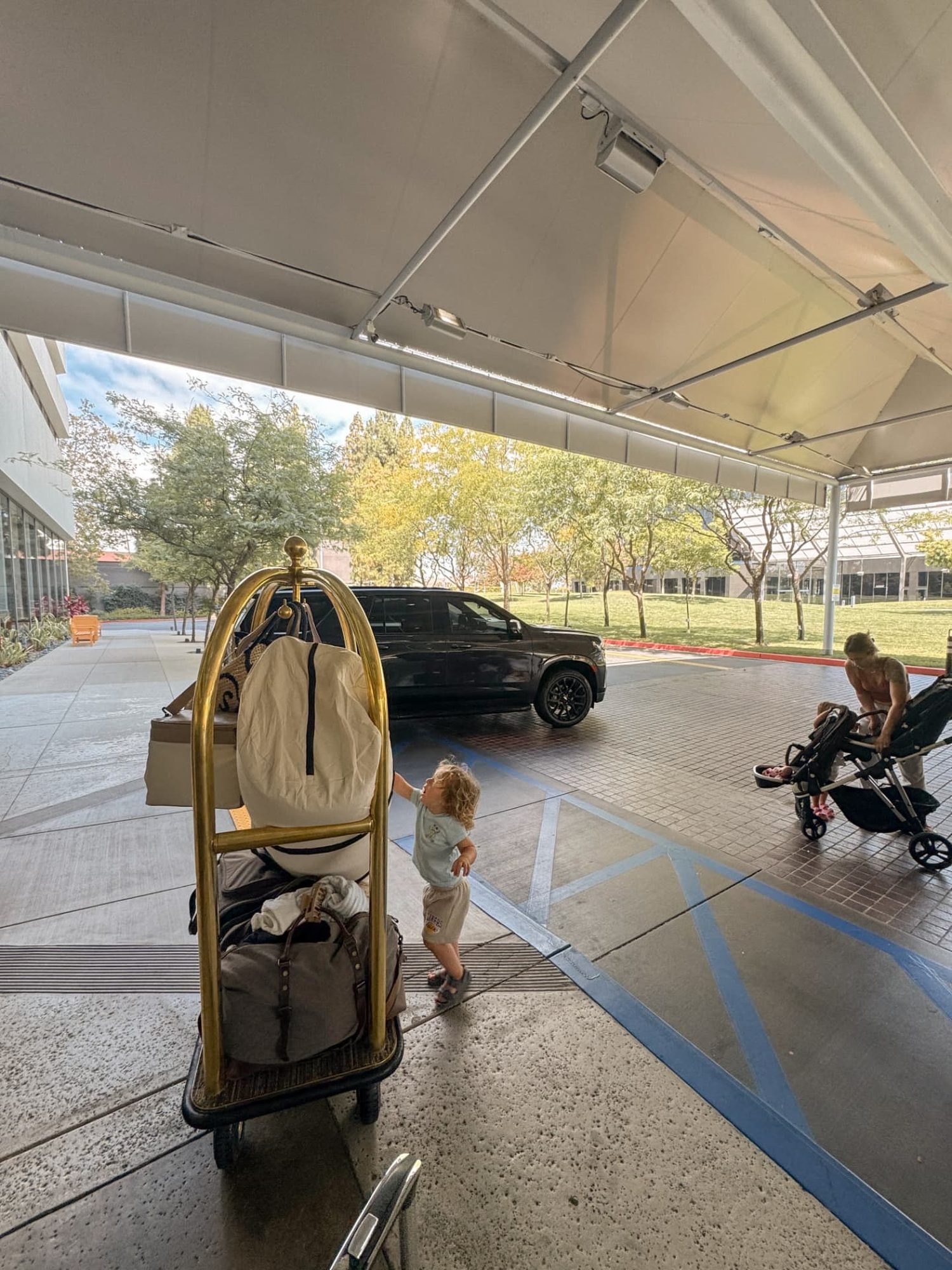 Toddler standing beside the family's loaded luggage cart while checking into The Westin South Coast Plaza