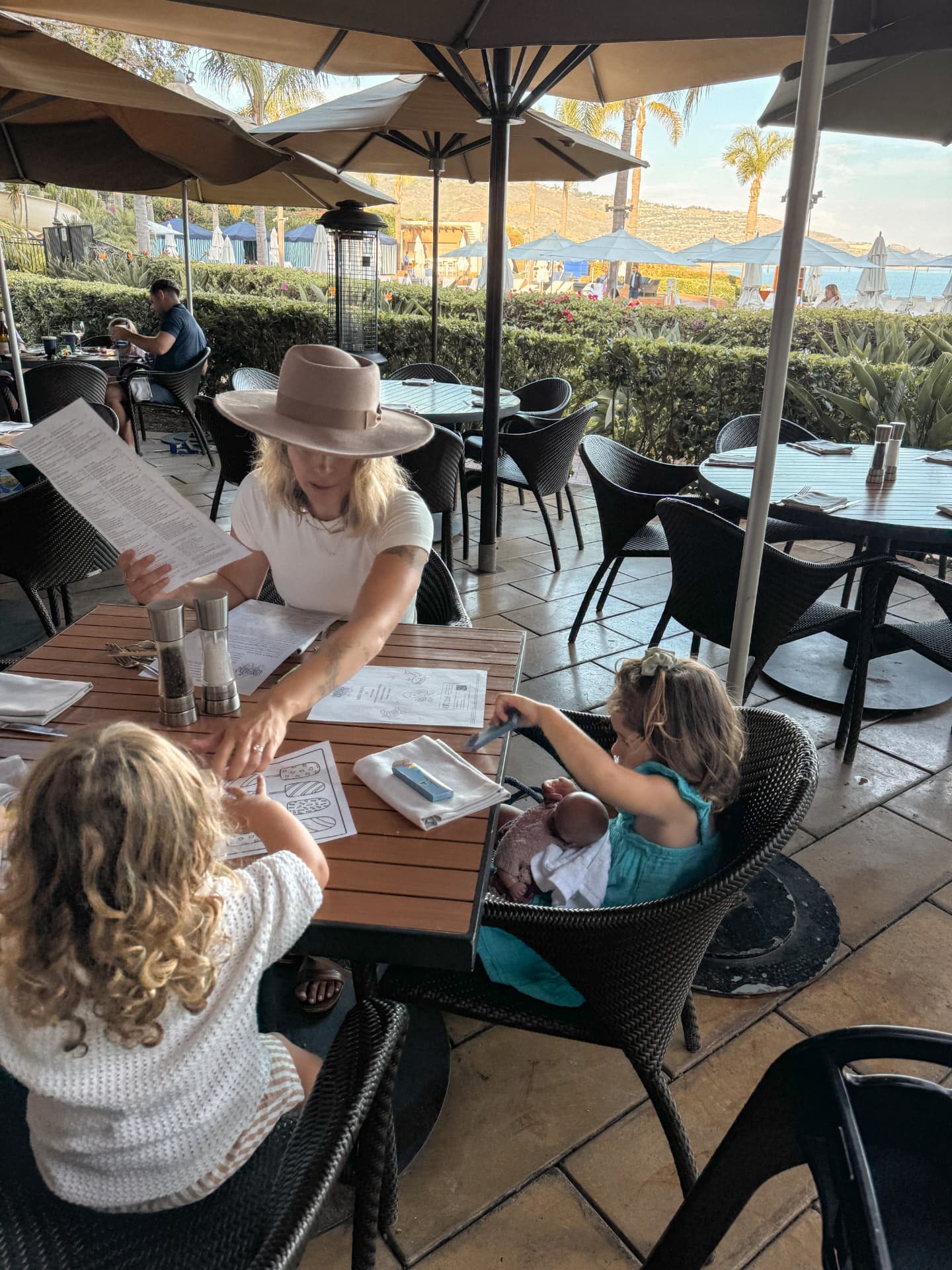Our table on the covered patio at catalina kitchen at Terranea, set with a kids' menu and crayons, with the resort beyond