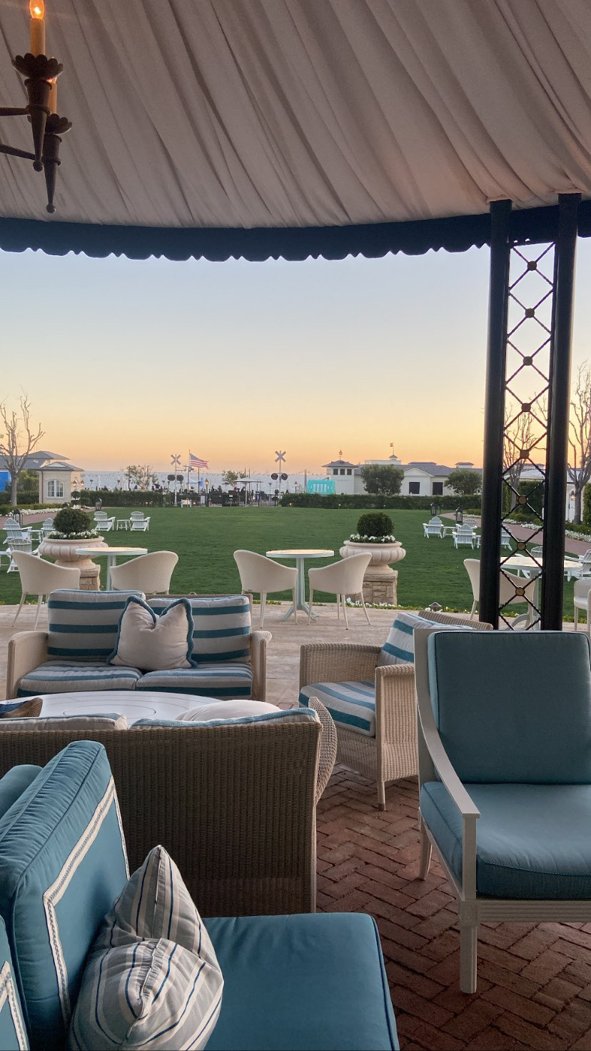 A striped canopy lounge looking out over a lawn to the ocean at dusk