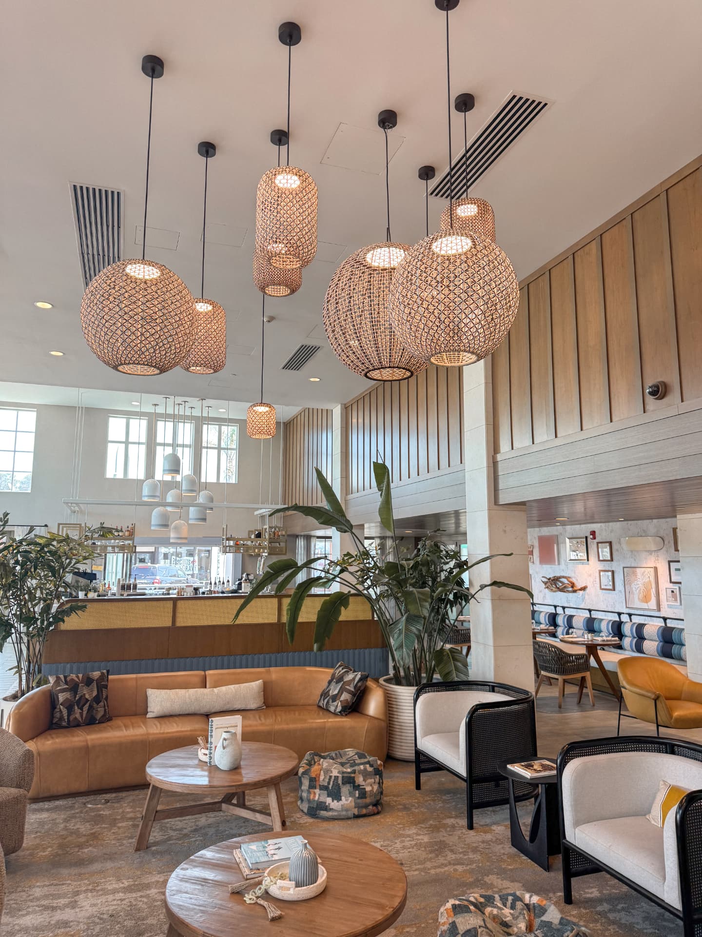 The bright coastal lobby at Inn at the Pier in Pismo Beach, with woven pendant lights, couches and open floor space