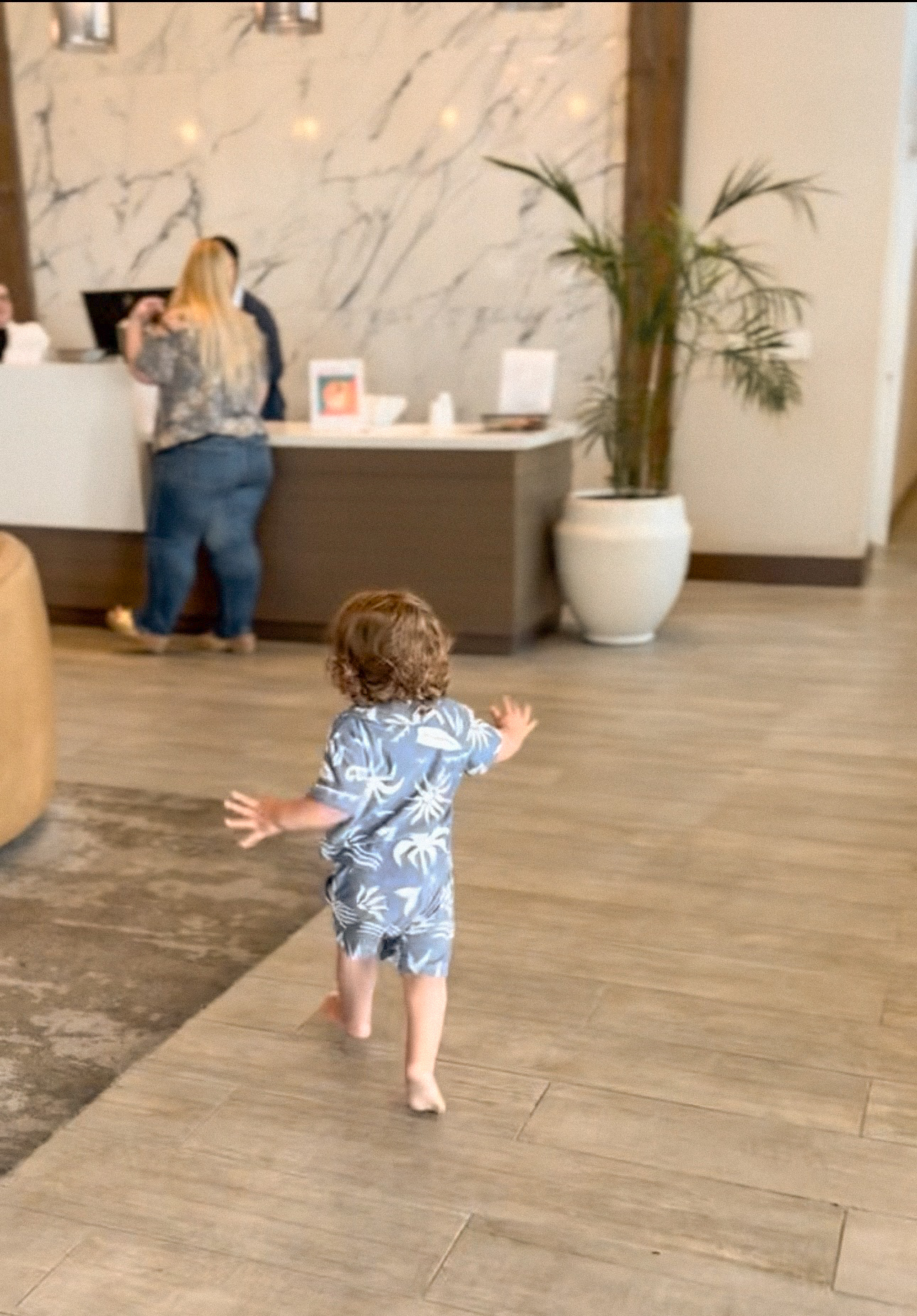 A small child walking ahead of the family towards a hotel reception desk